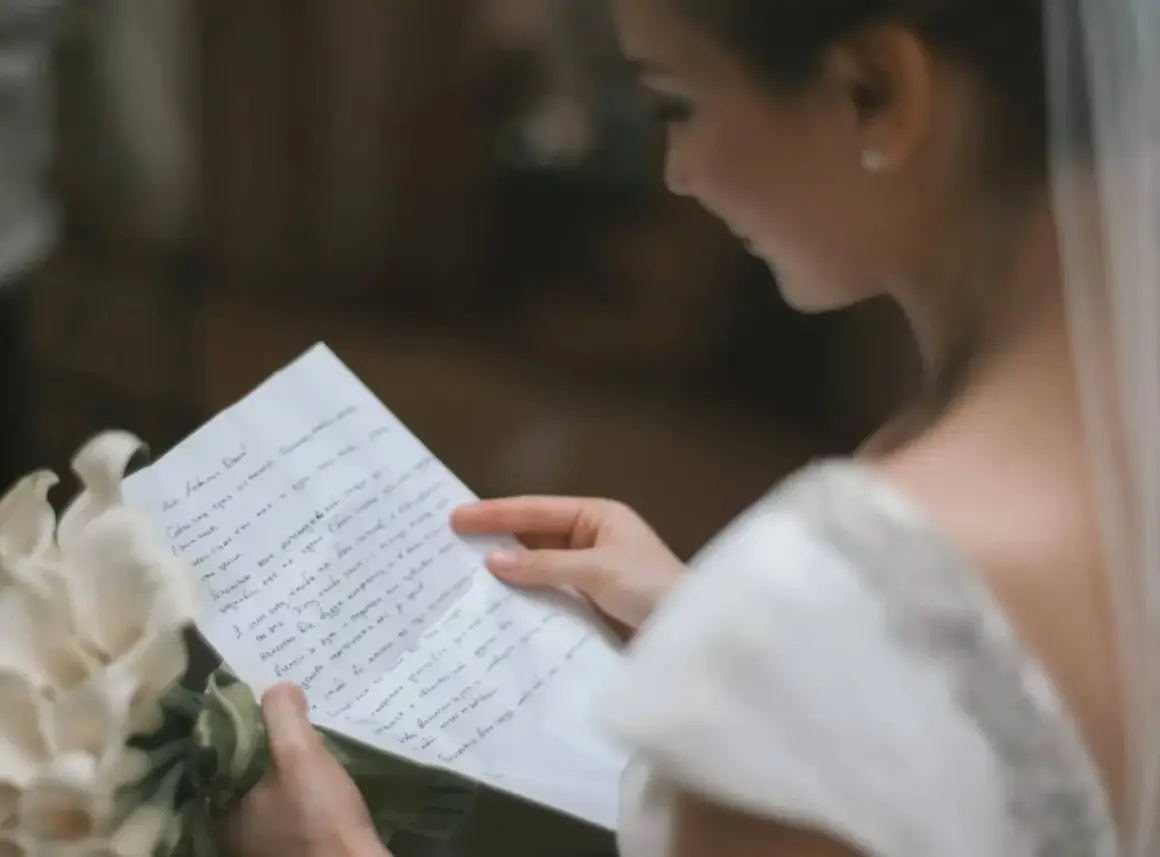 Une mariée lit une lettre d'intention mariage, un bouquet de callas à ses côtés.