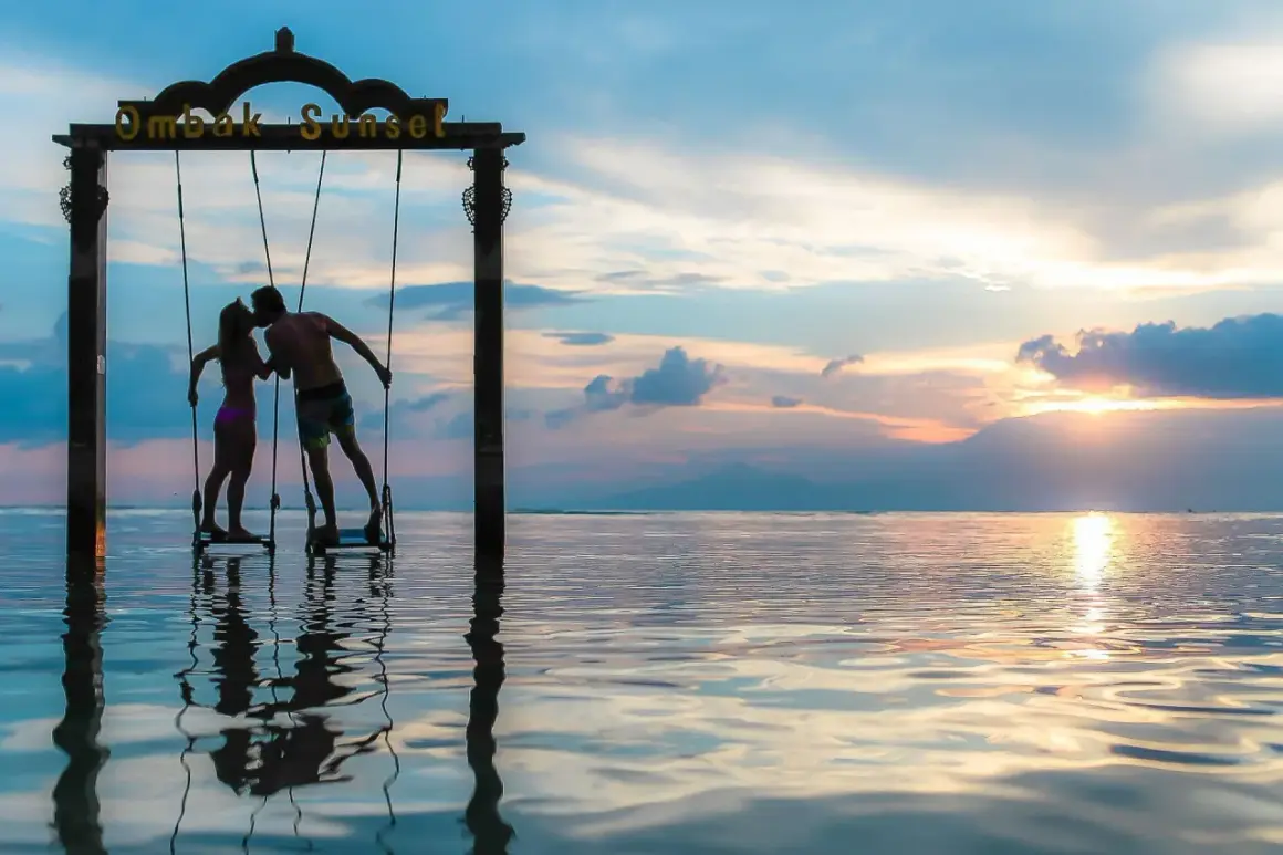 Couple s'embrassant sur des balançoires au coucher du soleil, une parfaite destination lune de miel pas cher.