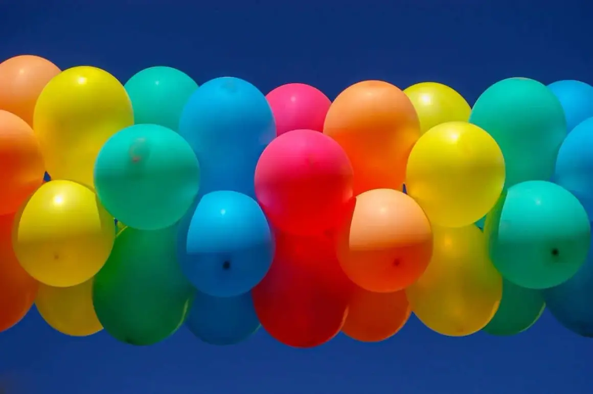 Un amas de ballons colorés flottant dans un ciel bleu. Combien de temps tient un ballon gonflé à l'air ? Cela dépend de sa taille et du matériau.