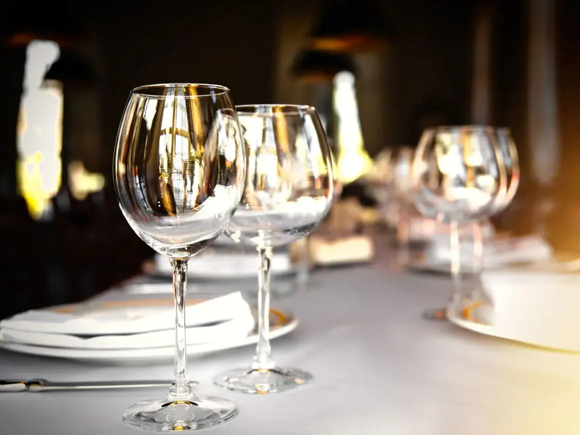 Trois verres à vin vides sur une table dressée, prêts pour un repas. Chaque verre reflète la lumière, comme un marque place verre.