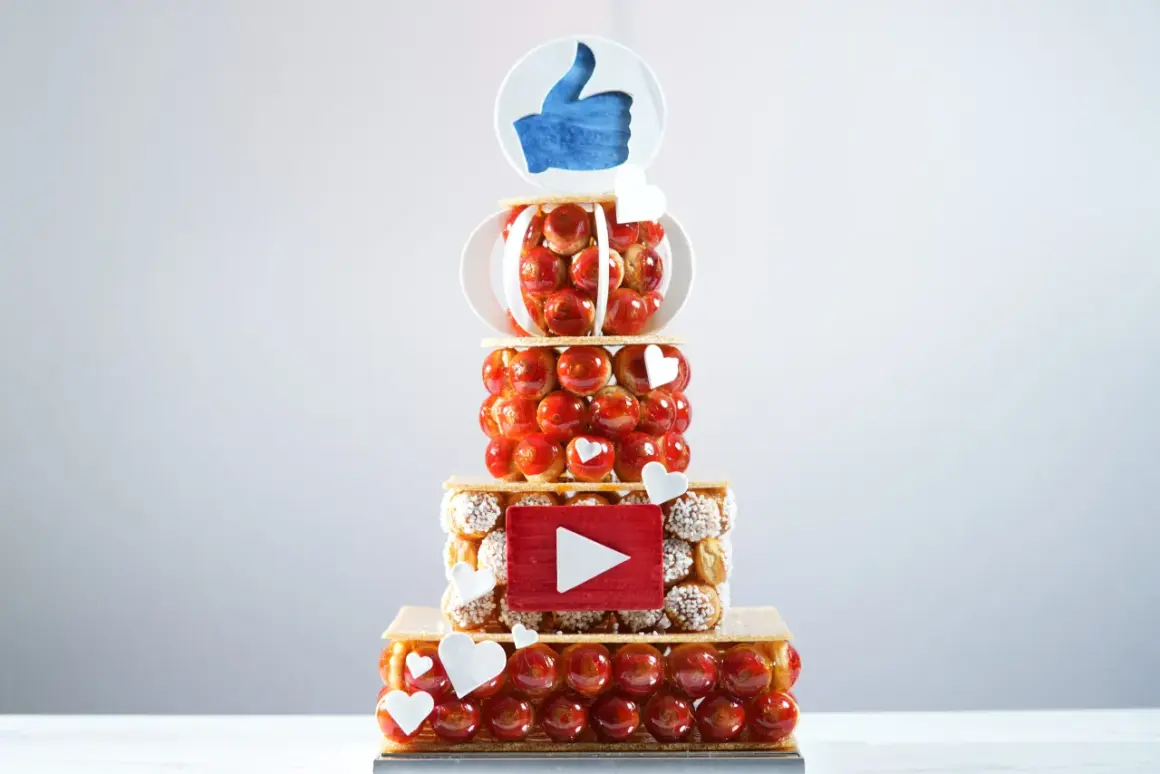 Pièce montée en choux, décorée d'un pouce levé et d'un logo YouTube. Peut-on faire une pièce montée en choux la veille ? Oui, pour un résultat aussi réussi !