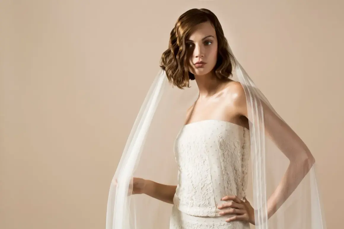 Une mariée porte une robe bustier en dentelle et un voile aérien, une création Delphine Manivet.