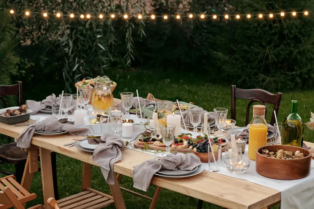 Table dress&eacute;e pour un d&icirc;ner en plein air, ambiance festive avec guirlandes lumineuses. Un jeune mari&eacute; pourrait y c&eacute;l&eacute;brer son union.