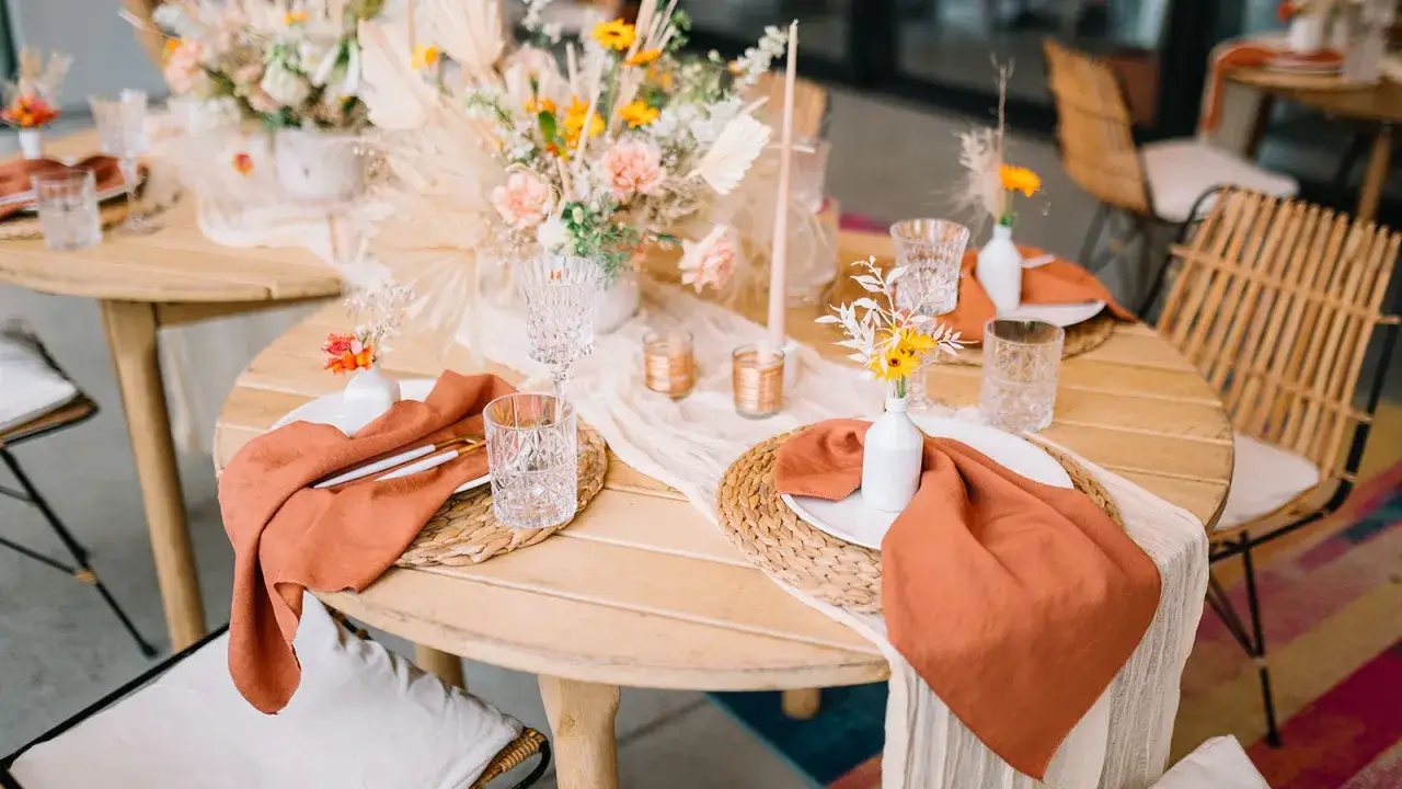 Table dressée pour un mariage bohème : nappes en lin ocre, fleurs séchées, bougies et vaisselle élégante.