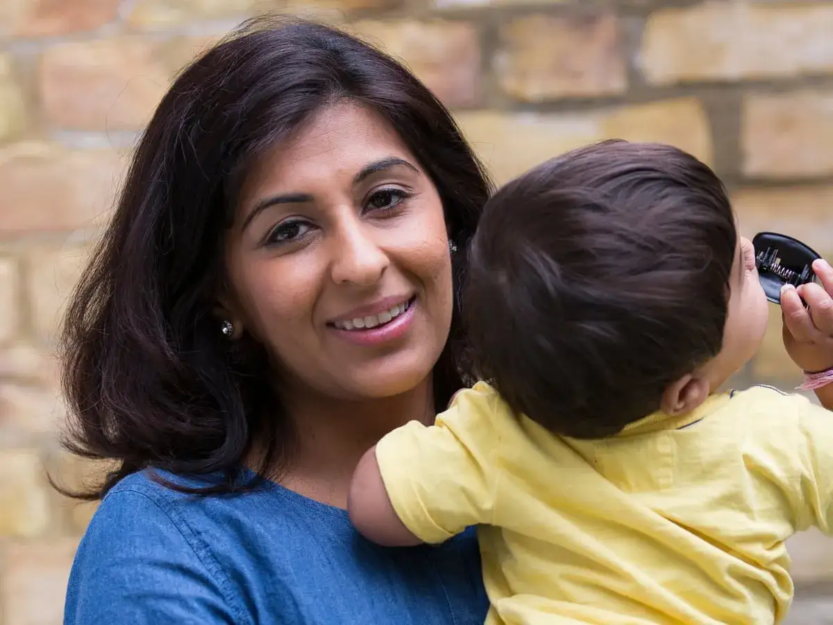 Une mère souriante tient son bébé, peut-être avant de lui raser les cheveux de bébé islam.