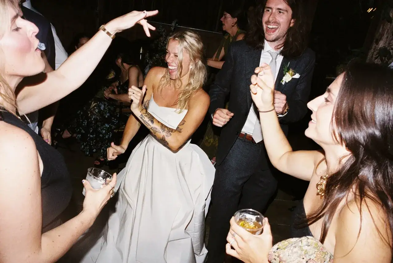 La mari&eacute;e, en robe blanche, danse joyeusement avec ses invit&eacute;s. La musique bat son plein, l'ambiance est festive, bien avant le g&acirc;teau de mariage.