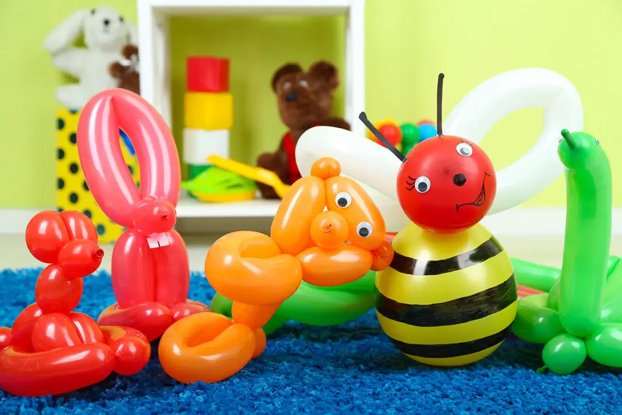 Sculptures de ballons faciles : un lapin rouge, un chien orange, une abeille et un ver vert sur un tapis bleu.