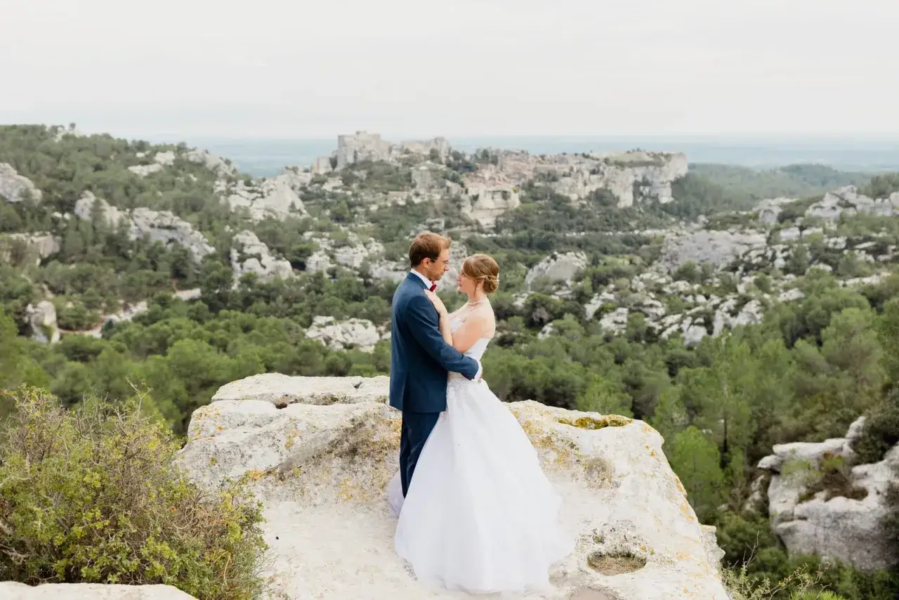 Un couple s'embrasse sur un rocher, avec un village perché en arrière-plan. Une belle photo d'engagement.