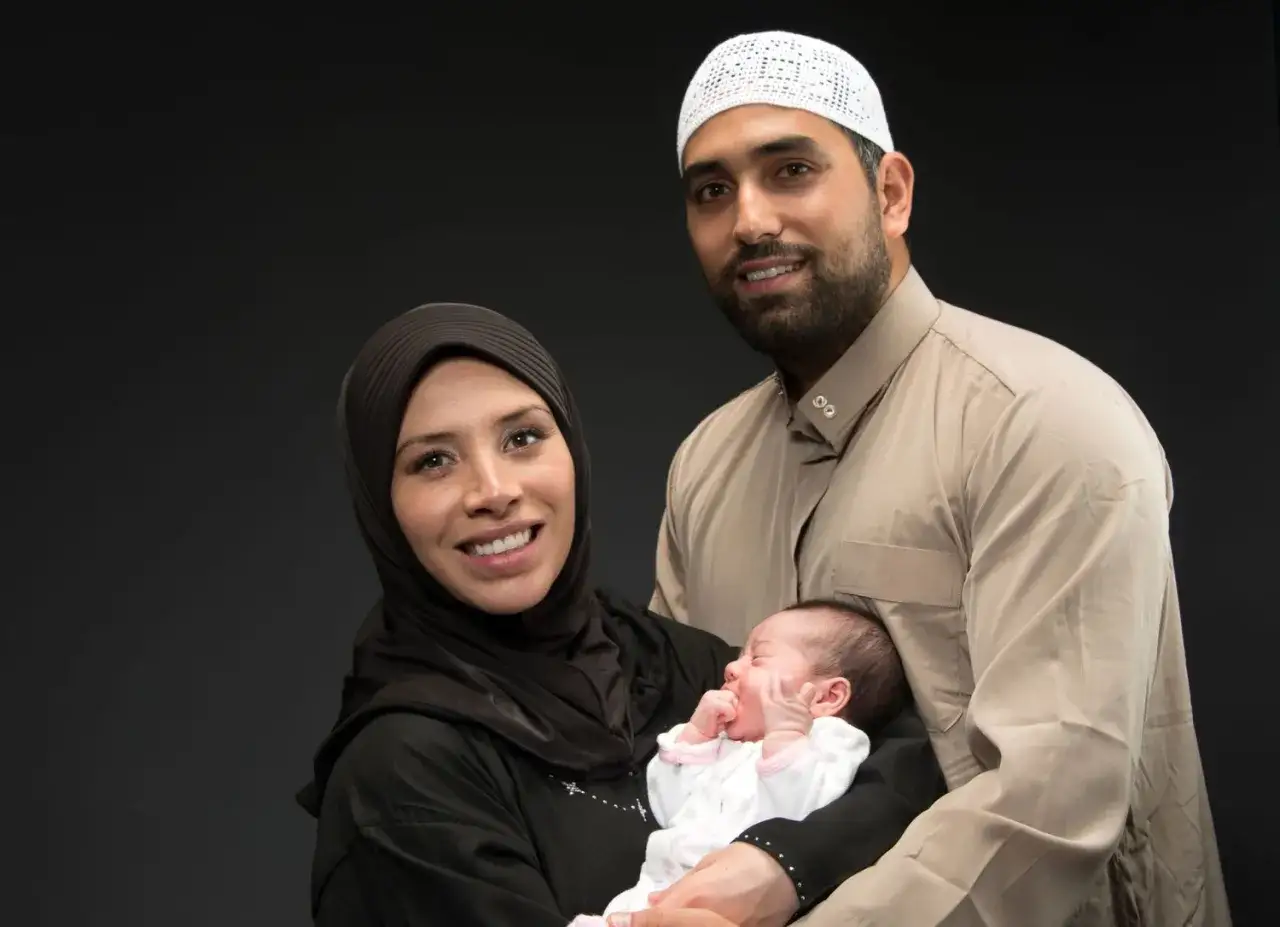 Un couple musulman célèbre la naissance de leur bébé. Le père porte une tenue traditionnelle, la mère un hijab. Un nouveau mouton de vie dans l'islam.
