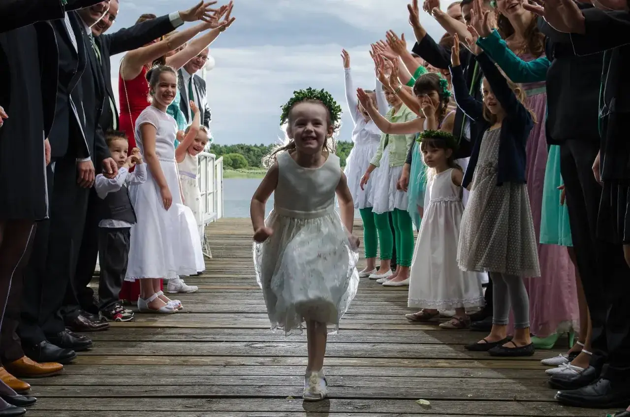 Une petite fille court sur un ponton, entourée de sa famille et d'amis qui l'acclament, célébrant son baptême laïque.