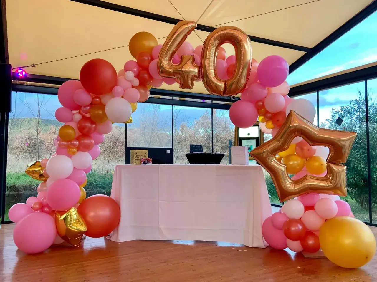 D&eacute;coration festive pour un 40&egrave;me anniversaire avec une arche de ballons roses, corail et dor&eacute;s, incluant des chiffres 
