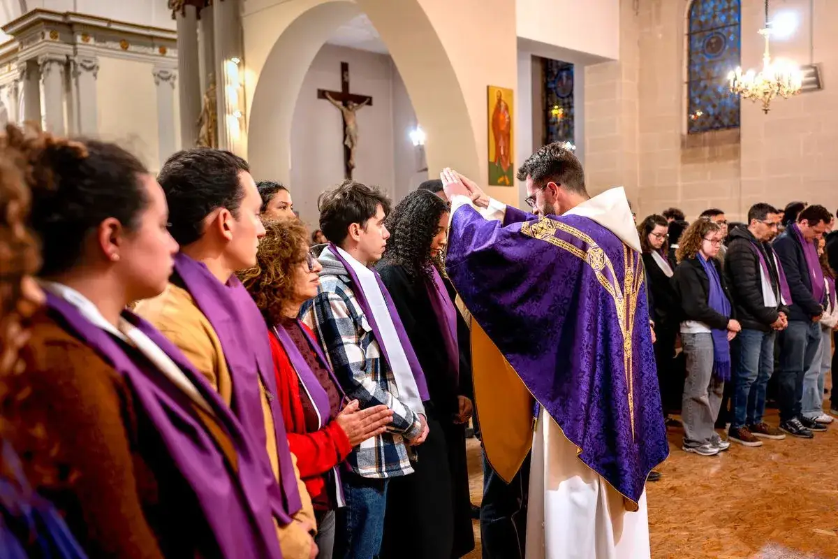 Un prêtre bénit des fidèles en robe violette. Ils se préparent pour un baptême. Que dire au prêtre pour un baptême ?