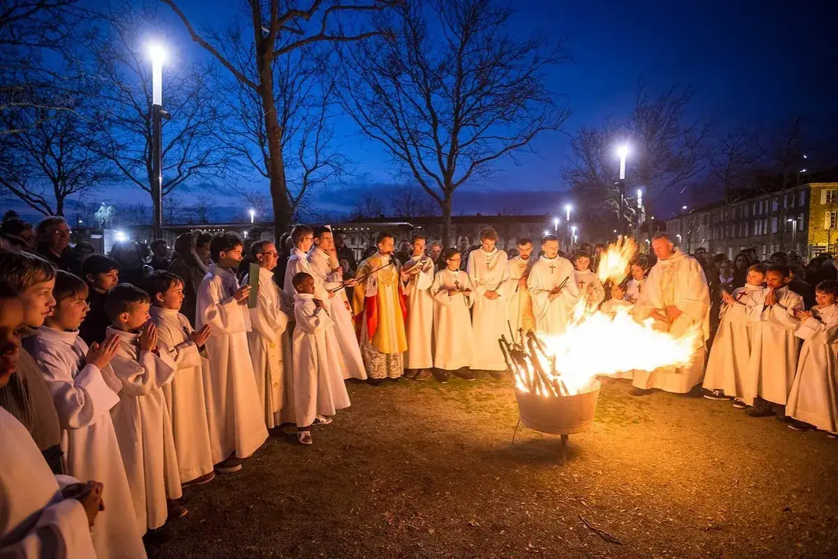 Cérémonie de la fête de Pâques, avec des enfants en robe blanche autour d'un feu. Une scène qui évoque l'origine de cette célébration.
