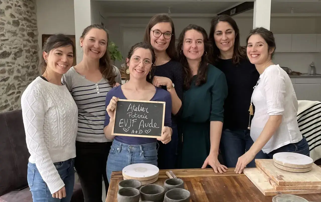 Groupe de femmes souriantes dans un atelier de poterie, parfait pour des idées enterrement de vie de jeune fille original.