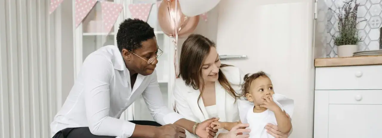 Famille souriante, prête à célébrer un baptême. La petite fille, en robe blanche, est le centre de l'attention.