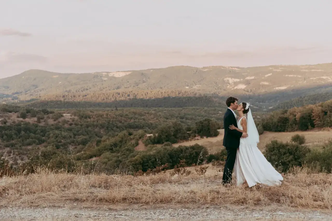 Un couple s'embrasse lors d'un elopement mariage, avec un paysage de collines verdoyantes en arrière-plan.