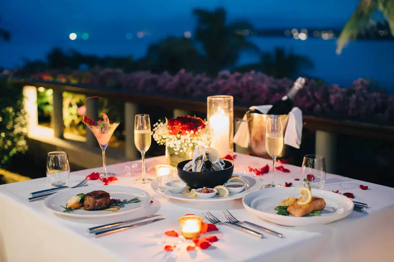 Dîner romantique pour un anniversaire de mariage : mets fins, champagne et bougies sur une terrasse au crépuscule.