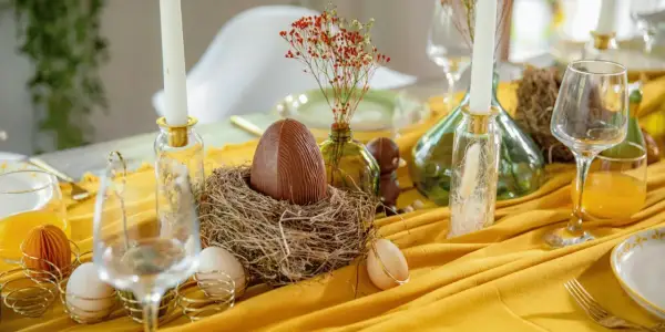 Un grand œuf en chocolat dans un nid, entouré d'œufs et de bougies, pour un joyeux dimanche de Pâques.