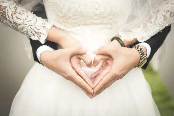 Les mains du jeune marié et de sa mariée forment un cœur sur la robe de mariée.