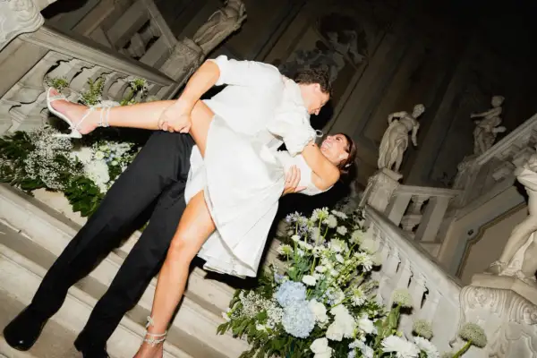 Un couple s'embrasse passionnément sur un escalier orné de fleurs, célébrant leur jour du mariage.
