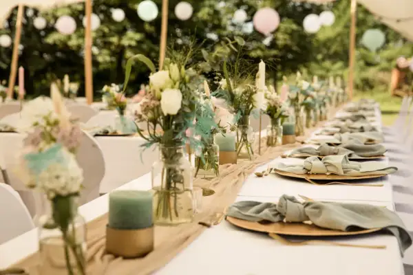 Décoration de chaise de mariage fait maison : table dressée avec des fleurs, des bougies et des serviettes en tissu nouées.