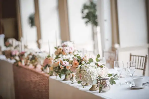 Magnifique centre de table floral pour un mariage, avec des roses pâles et des hortensias blancs. Une bougie mariage subtile complète la scène.