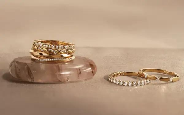 Pile d'alliances en or et diamants sur une pierre, et deux autres bagues serties de diamants. Comment choisir son alliance ?