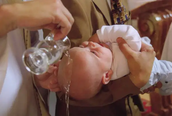 Un bébé est baptisé, l'eau bénite coule sur sa tête. Un moment solennel pour comprendre pourquoi baptiser son enfant.