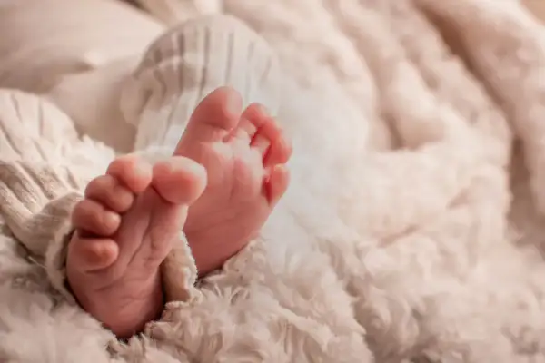 Petits pieds de bébé, tendrement enveloppés dans une couverture douce. Une image symbolisant la pureté et le début d'une nouvelle vie, peut-être en attente de la circoncision islam 7 jours.