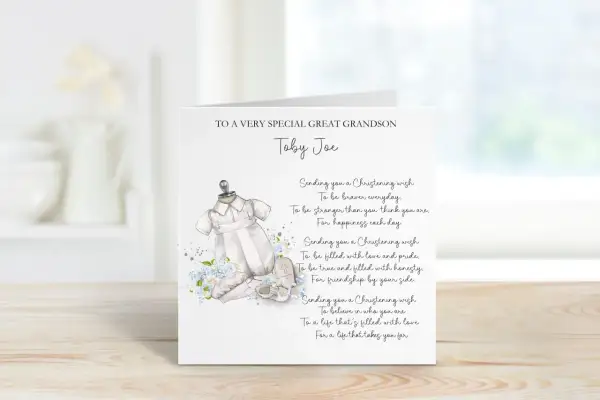 Carte de baptême pour Toby Joe, avec une tenue de bébé et des fleurs bleues. Un doux message de baptême pour un petit-fils.