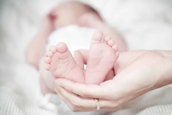 Les petits pieds d'un nourrisson de 40 jours, tendrement tenus dans des mains. Une image évoquant la douceur et la pureté, souvent associée aux traditions islamiques.